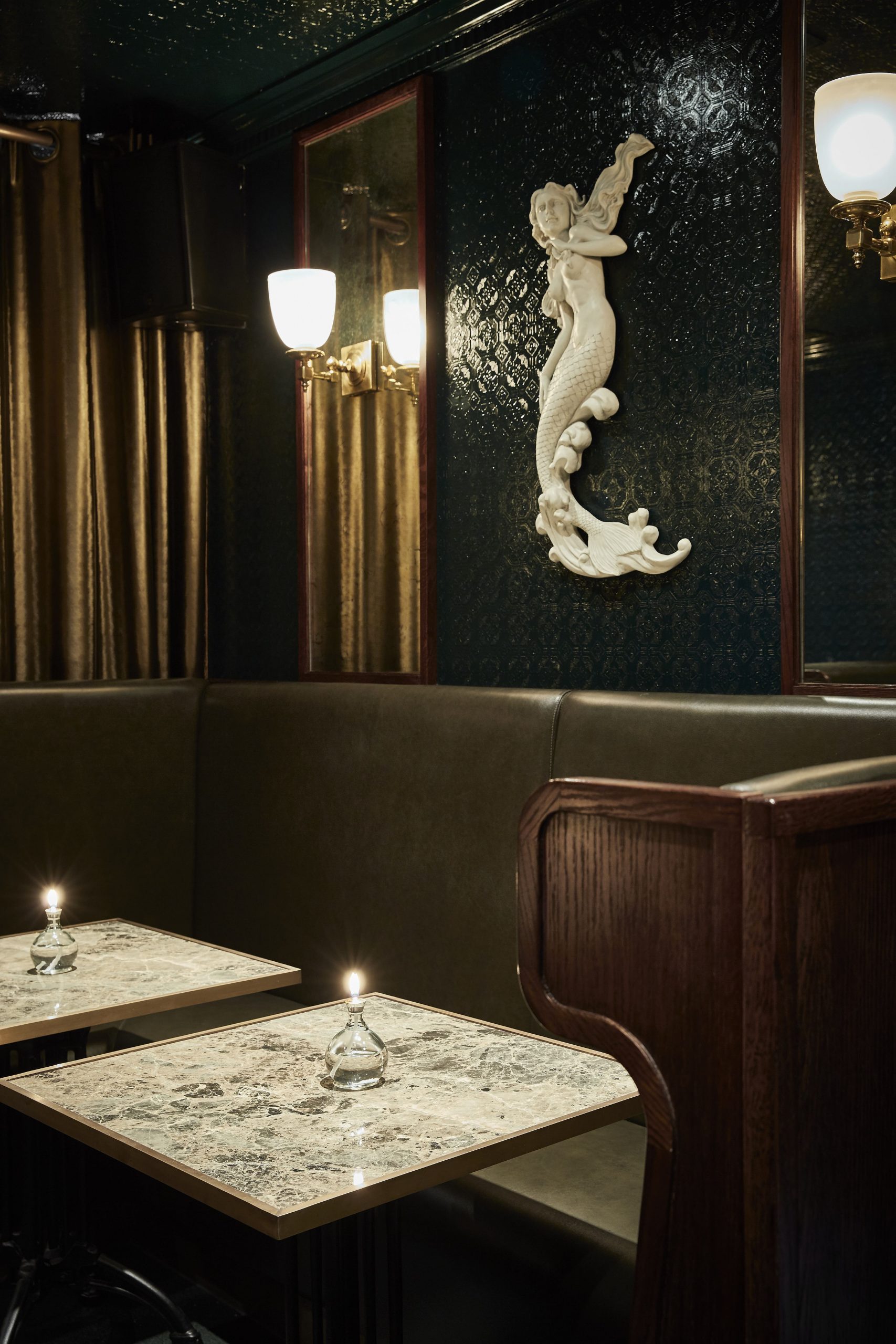 Banquette seating area with mermaid sculpture on wall