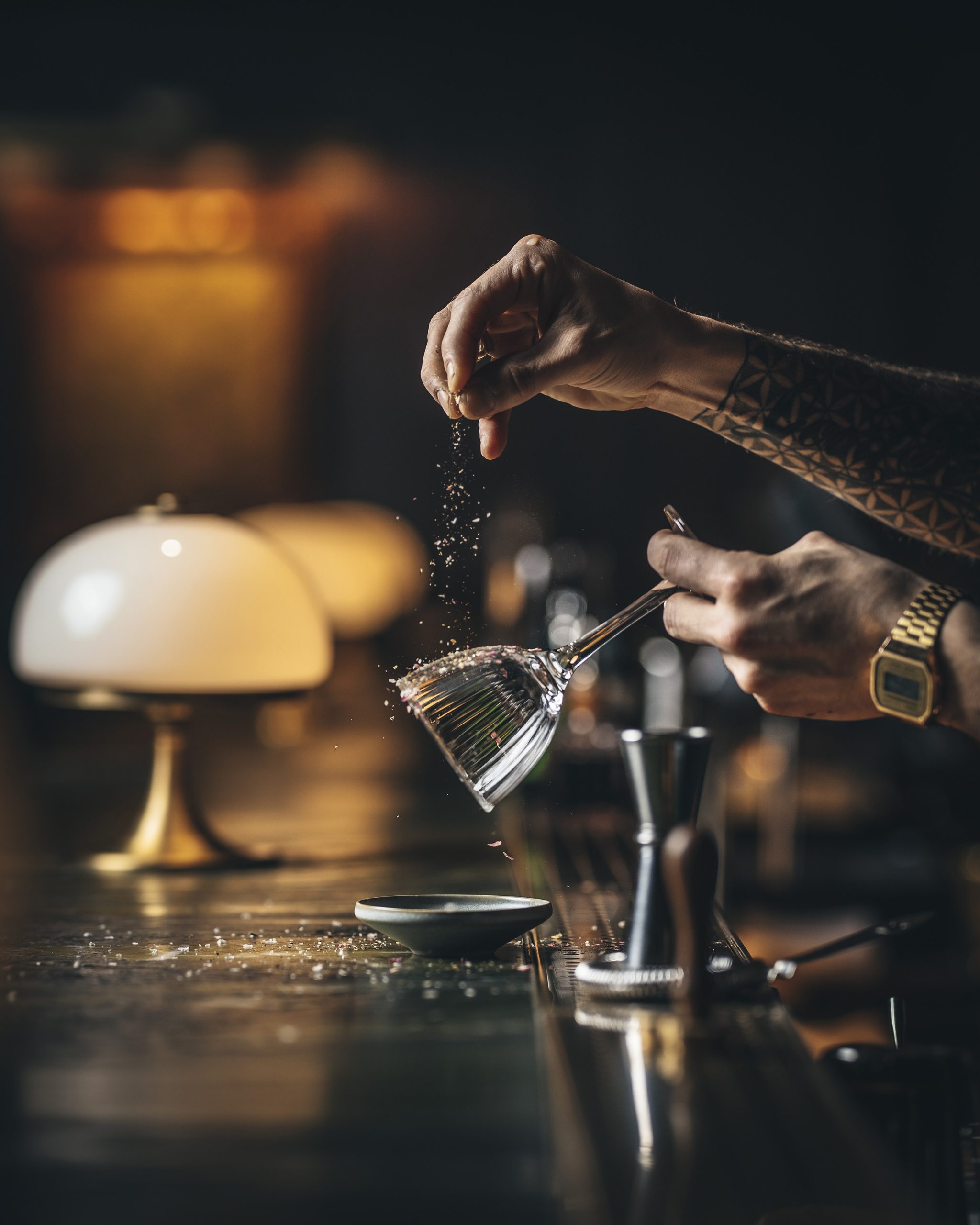 Gourmet touch: Bartender salts glass alongside ambient lamps