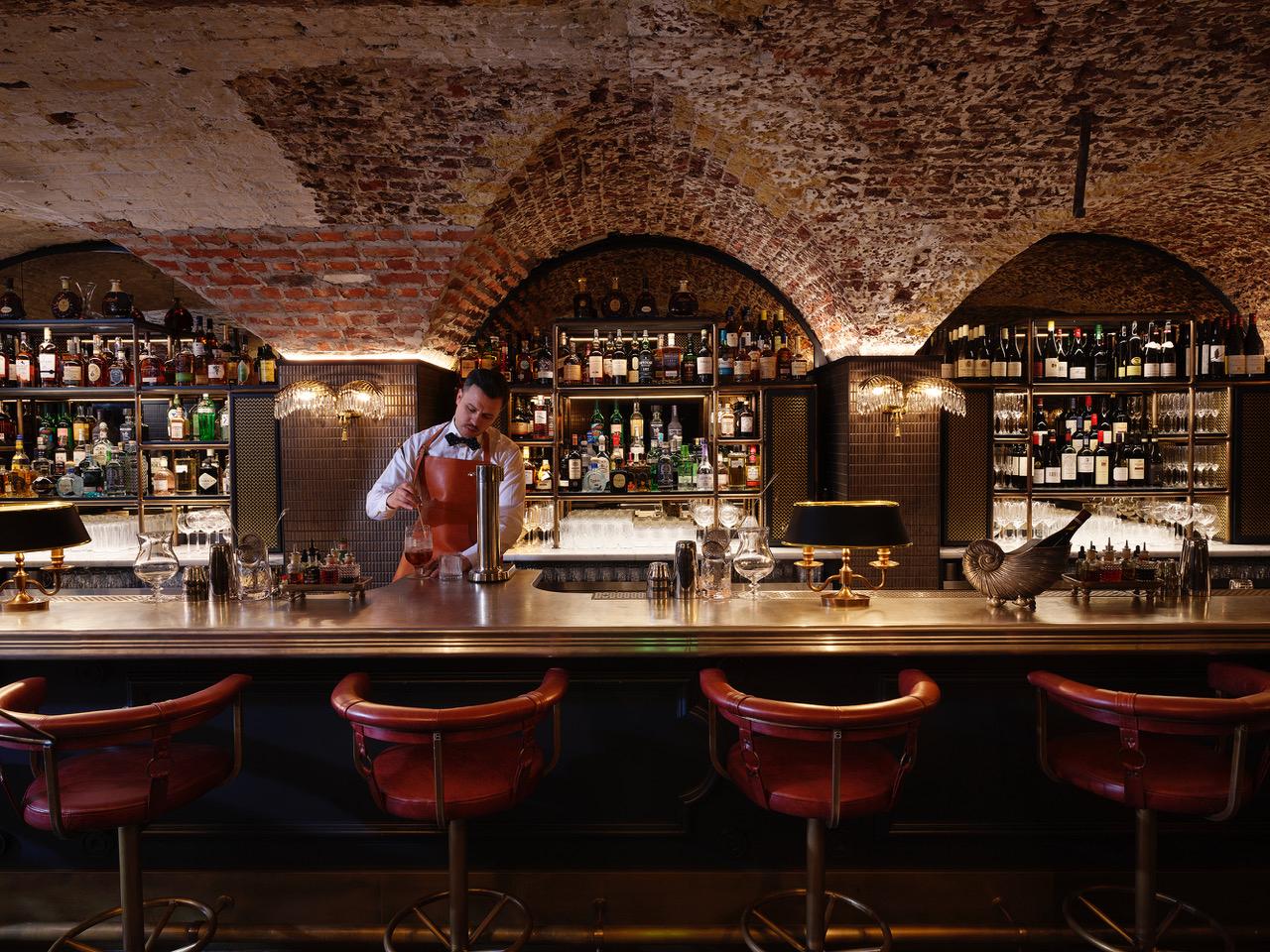 Luxury tavern bar with exposed brick walls, bartender crafting drinks