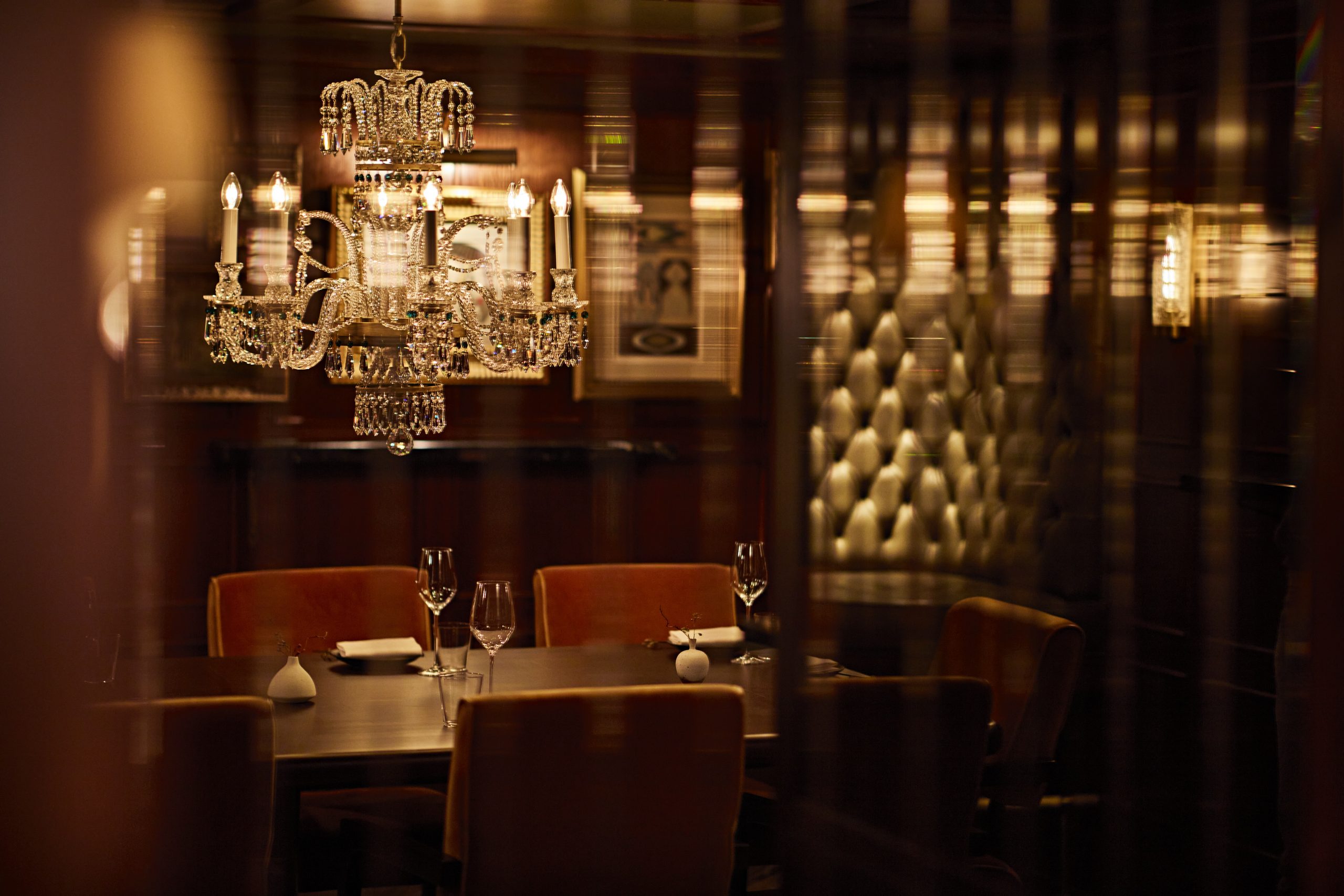 Private Dining Elegance: Ornate glass chandelier, wooden table, warm lighting