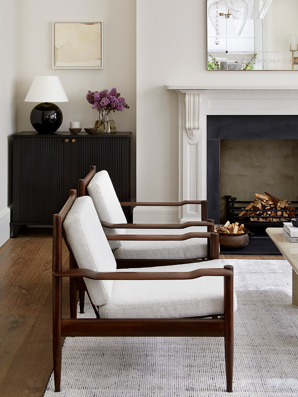 A period fireplace with antique armchairs and bespoke cabinet